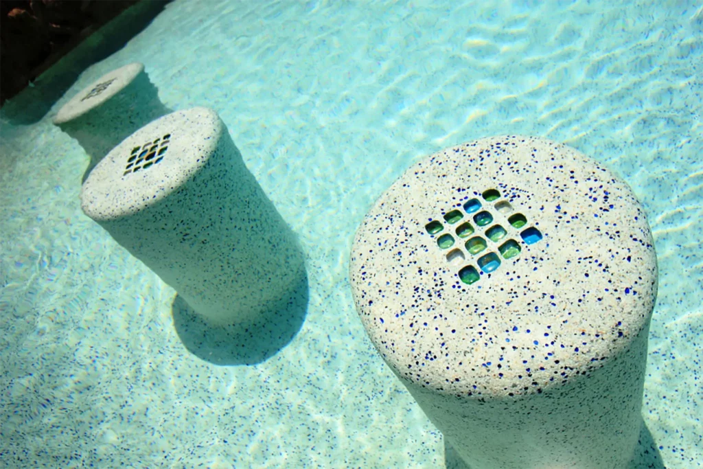 A closeup of stone-scaping features in a clear, light blue pool.