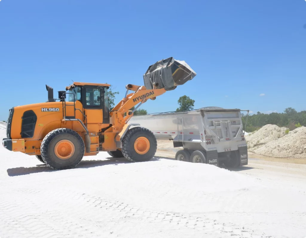 Loading equipment dumps sand into a tractor trailer in a sand quarry.