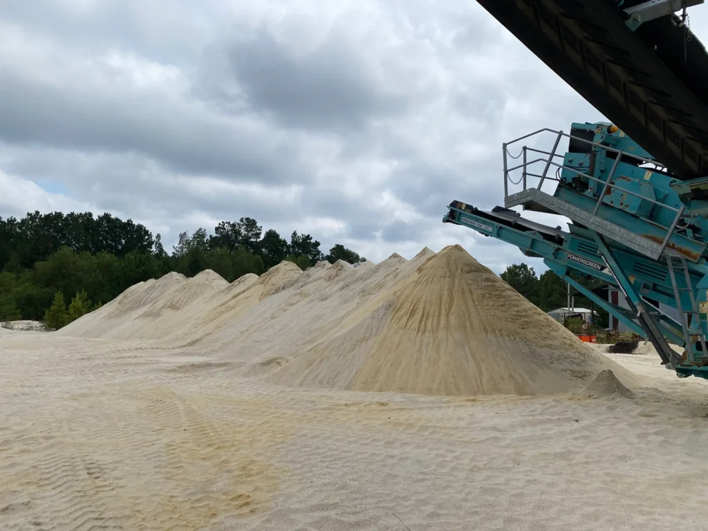 A conveyer is being used to sift sand into a piles of Premier sand products.